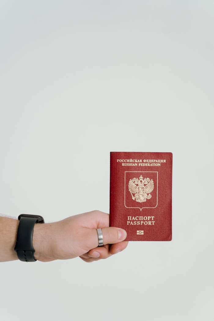 gallery-4 Close-up of a hand holding a Russian Federation passport on a white background.
